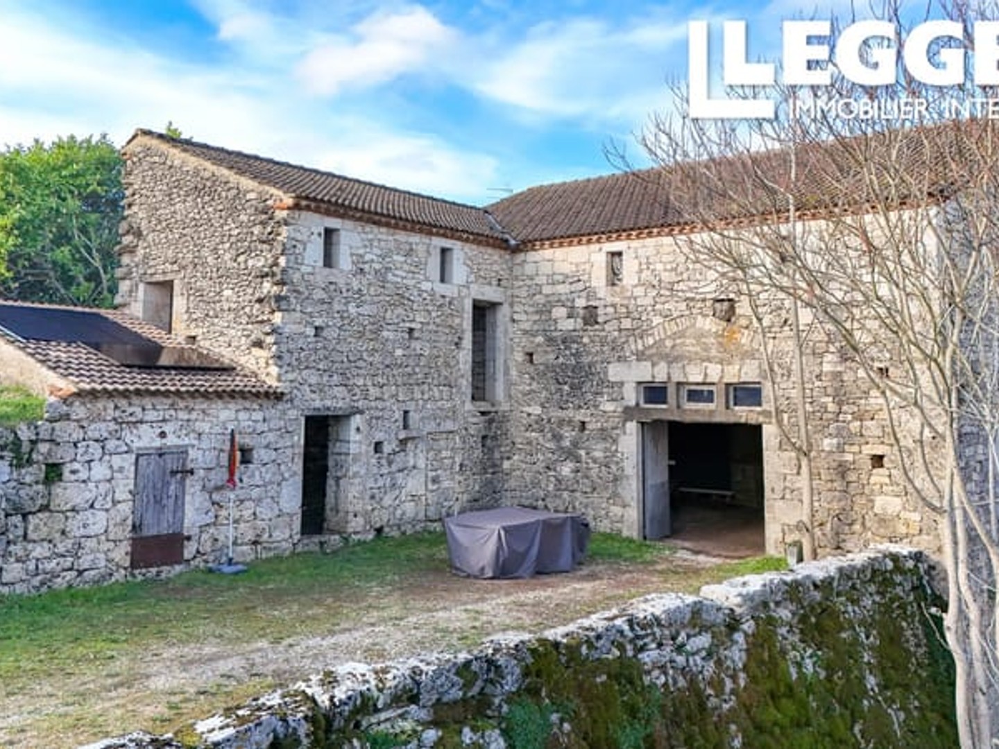 Grange en pierre à rénover, située au calme mais au centre du village, avec jardin et bois en pente.